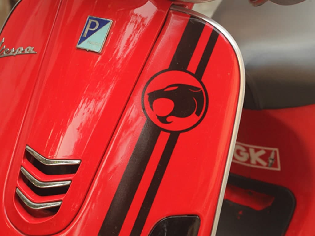 A red Vespa with a custom decal on the front shield